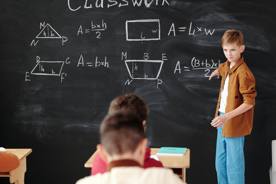 Ein Junge steht an der Tafel und erklärt Mathe