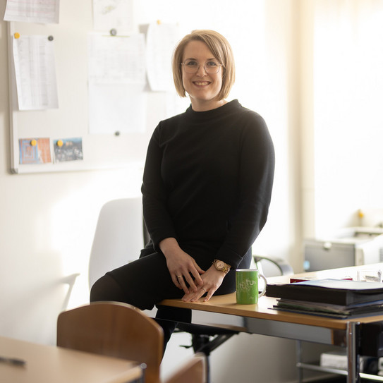 Frau sitzt seitlich auf einem Tisch und schaut in die Kamera