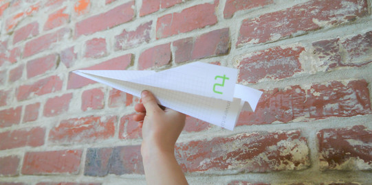 Papierflieger vor einer Wand