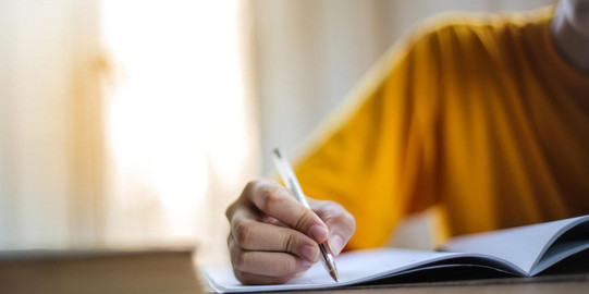 Person die mit einem Stift auf Papier schreibt