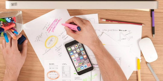 Lernmaterialien Draufsicht auf einen Schreibtisch mit Handy und Unterlagen