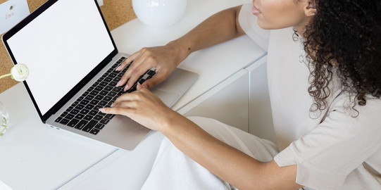 Frau sitzt am Schreibtisch mit Laptop