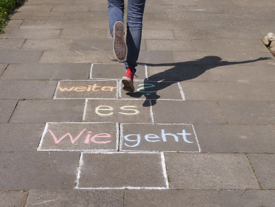 Wie geht es weiter? Person hüpft über gemalte Steine