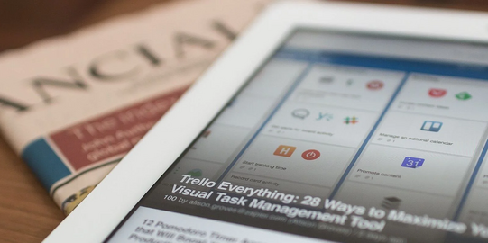 Tablet und Zeitung liegen auf Tisch
