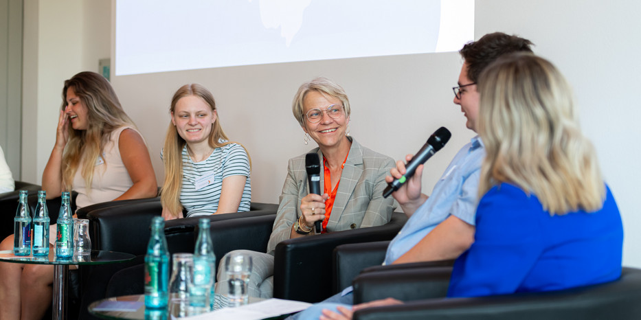 Fünf Personen sitzen auf einem Podium und diskutieren