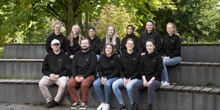 Ein Gruppenfoto von 12 Personen in gleichen Pullover