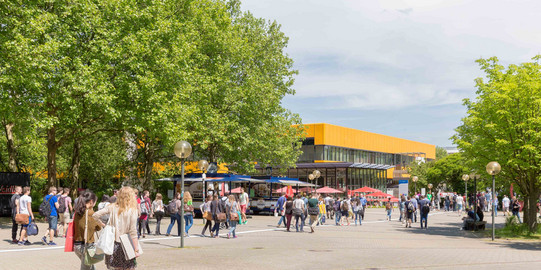 Studierende auf dem Campus Nord mit der Hauptmensa im Hintergrund im Sommer