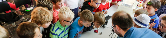 KinderUni im U Kinder im Grundschulalter schauen sich Versuchsanordnung an