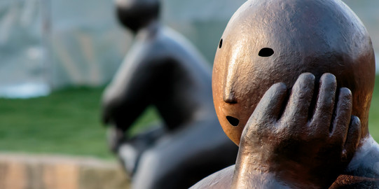 Massive Steinfiguren in nachdenklicher Pose. 