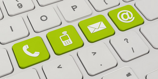 Auf einer weißen Tastatur sind vier Tasten grün eingefärbt. Darauf zu sehen sind Symbole für ein Telefon, ein Mobiltelefon, ein Briefumschlag und ein "at"-Zeichen.
